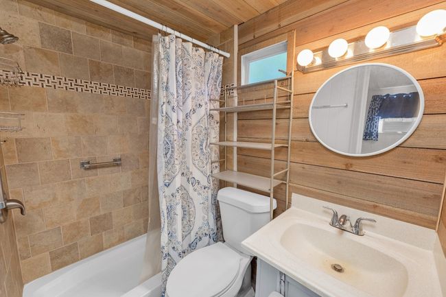 Bathroom with vanity, wood ceiling, shower / bath combo with shower curtain, and wooden walls | Image 22