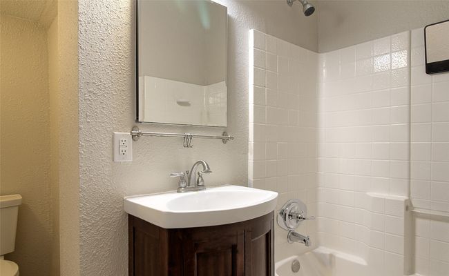 Bathroom with toilet, a textured wall, vanity, and shower / tub combination | Image 15
