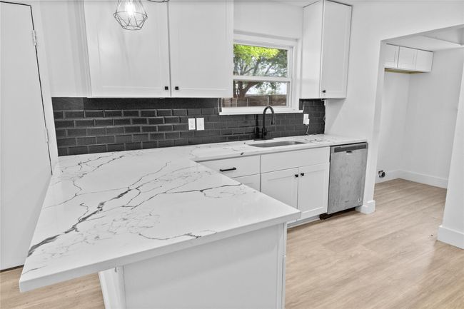 Kitchen with a sink, dishwasher, light wood-style flooring, and white cabinets | Image 12