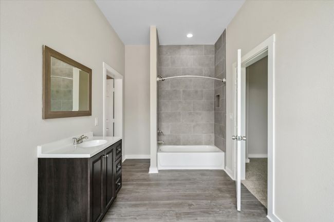Bathroom featuring vanity, wood finished floors, bathing tub / shower combination, and baseboards | Image 31