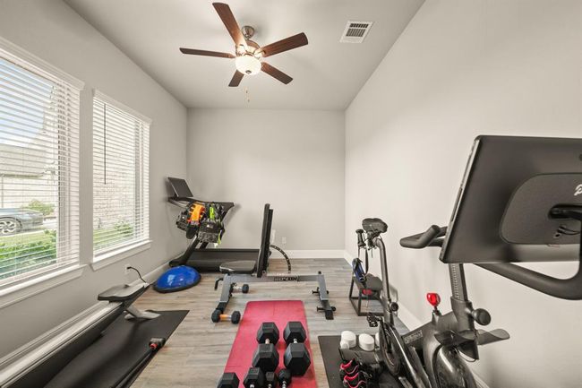 Dedicated home gym space with large windows and wood-look flooring on the 1st floor. | Image 38