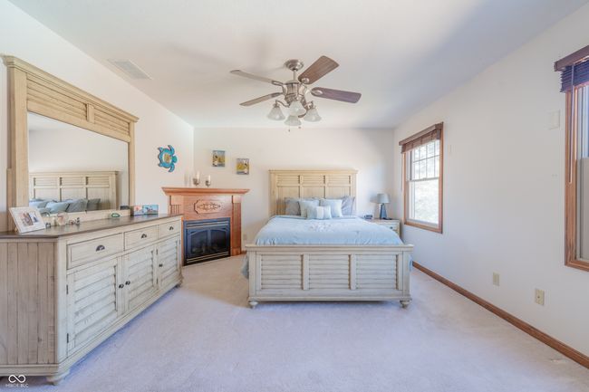 bedroom with a glass covered fireplace, visible vents, baseboards, and light carpet | Image 21