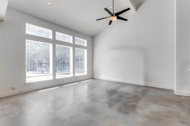 Spare room with concrete flooring, recessed lighting, high vaulted ceiling, baseboards, and a ceiling fan | Image 6