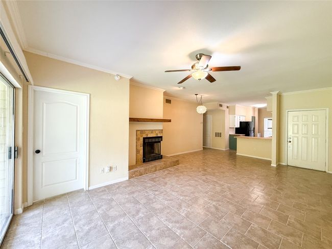 Unfurnished living room with a ceiling fan, a tiled fireplace, and ornamental molding | Image 9