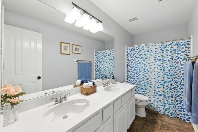 Full bath featuring double vanity, stone finish flooring, and a shower with curtain | Image 25