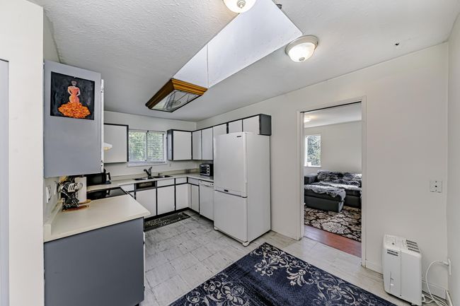 Kitchen featuring a sink, a textured ceiling, white appliances, white cabinets, and light countertops | Image 7