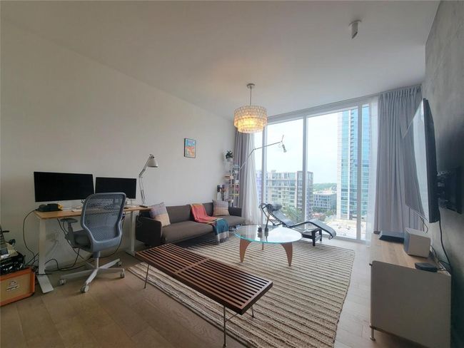 Living area with floor to ceiling windows, light wood finished floors, and a desk | Image 5