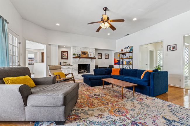 Living room with wood finished floors, ceiling fan, a brick fireplace, and recessed lighting | Image 6