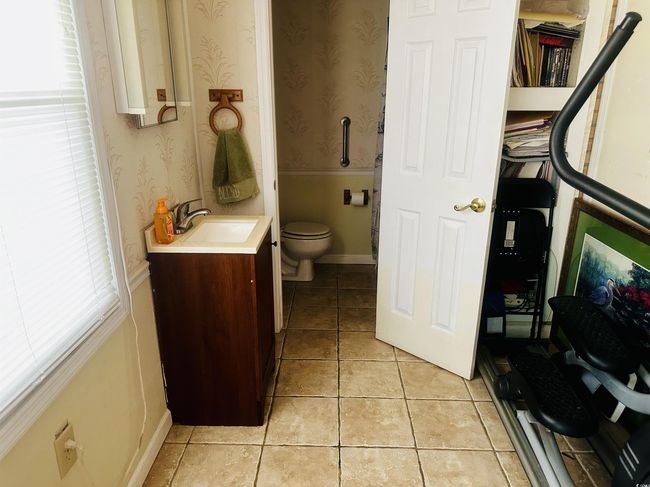 Bathroom with toilet, tile patterned floors, wallpapered walls, and vanity | Image 10