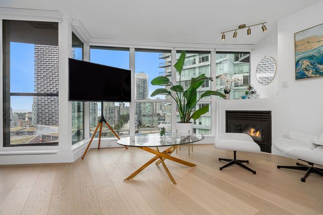 Unfurnished room with a wall of windows, a glass covered fireplace, wood finished floors, and plenty of natural light | Image 16