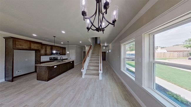 Kitchen featuring ornamental molding, stainless steel microwave, a sink, and light wood-style flooring | Image 17
