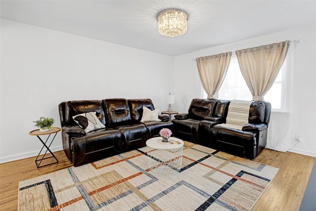 Living area featuring a chandelier, wood finished floors, and baseboards | Image 5