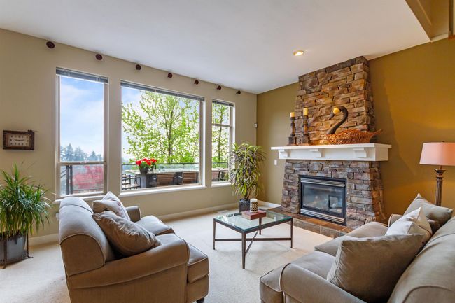 Carpeted living area featuring baseboards and a stone fireplace | Image 6