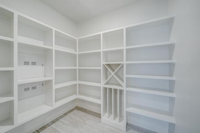 Spacious pantry with white built-in shelves and wine storage, offering ample storage space and a clean, modern look. | Image 5