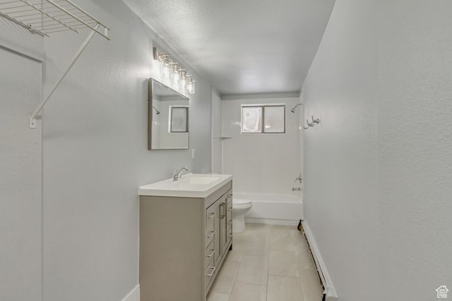 Bathroom with vanity, toilet, tile patterned flooring, baseboards, and tub / shower combination | Image 13