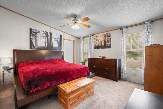 Primary Bedroom with ornamental molding, light colored carpet, a textured ceiling, lofted ceiling, and ceiling fan | Image 17