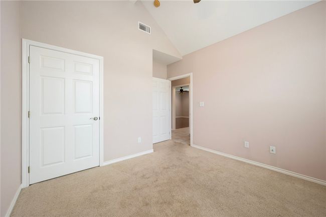 Unfurnished bedroom with carpet floors, high vaulted ceiling, baseboards, and ceiling fan | Image 13