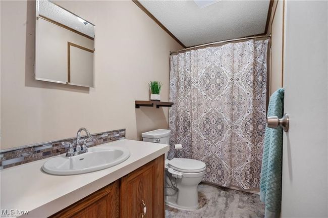 Bathroom with vanity, a textured ceiling, a shower with curtain, and tasteful backsplash | Image 17