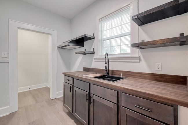 Kitchen with open shelves, butcher block countertops, light wood-style flooring, and dark brown cabinets | Image 31