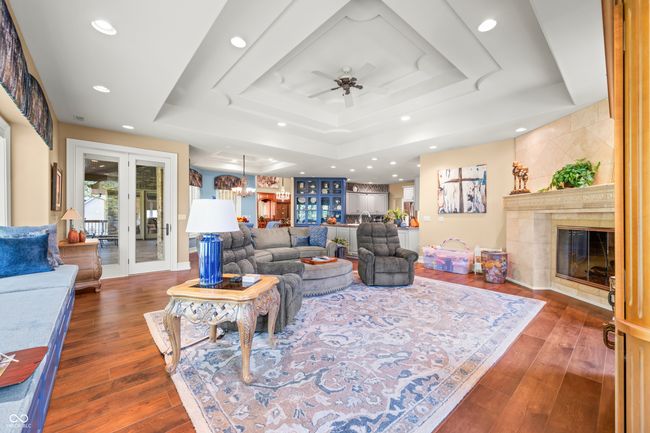living area featuring a tray ceiling, a tile fireplace, recessed lighting, dark wood finished floors, and a ceiling fan | Image 22