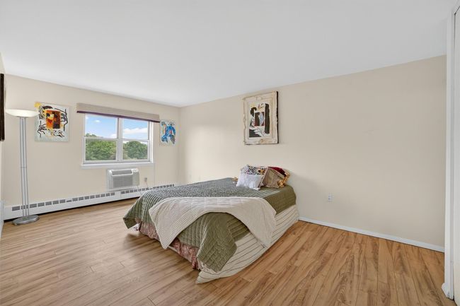 Bedroom with a baseboard radiator, wood finished floors, and a wall mounted AC | Image 26