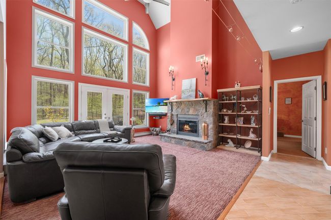 Living room featuring baseboards, a stone fireplace, high vaulted ceiling, recessed lighting, and french doors | Image 12