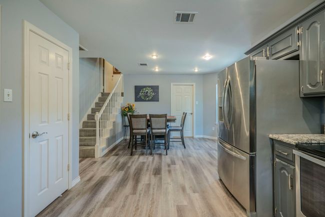 Kitchen with range, light wood-type flooring, stainless steel fridge with ice dispenser, gray cabinetry, and light stone countertops | Image 11