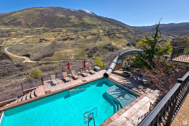 View of pool with a patio area, a mountain view, fence, and a water slide | Image 61