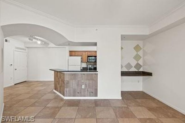 Kitchen with stove, arched walkways, ornamental molding, stainless steel microwave, and fridge | Image 12