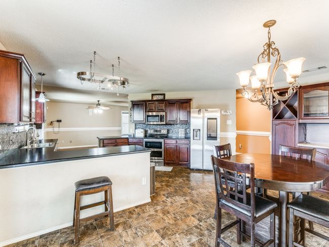 Kitchen featuring stainless steel appliances, backsplash, a ceiling fan, a chandelier, and a peninsula | Image 5