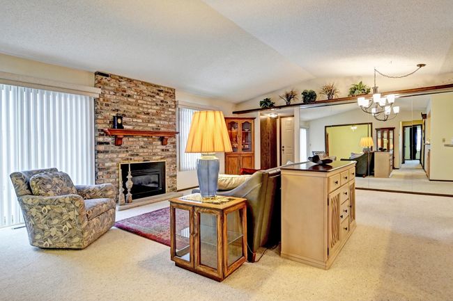 Living room has vaulted ceiling, brick fireplace, and sliding doors to patio | Image 5