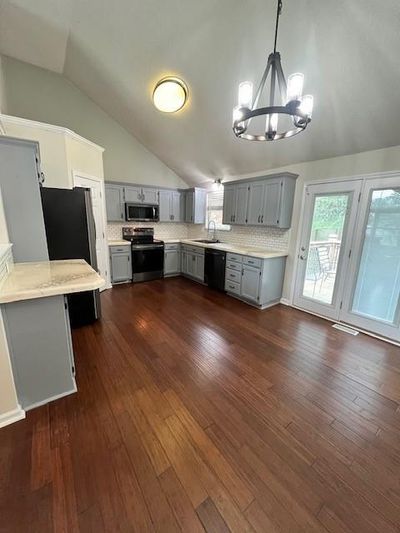 Kitchen with vaulted ceiling, sink, stainless steel appliances, and dark hardwood / wood-style flooring | Image 2