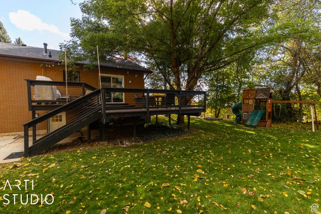View of grassy yard featuring a playground, a wooden deck, and stairway | Image 49