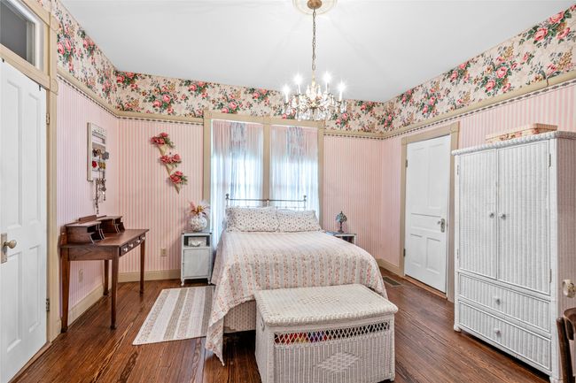 Bedroom featuring wallpapered walls, a chandelier, baseboards, and dark wood-style floors | Image 19