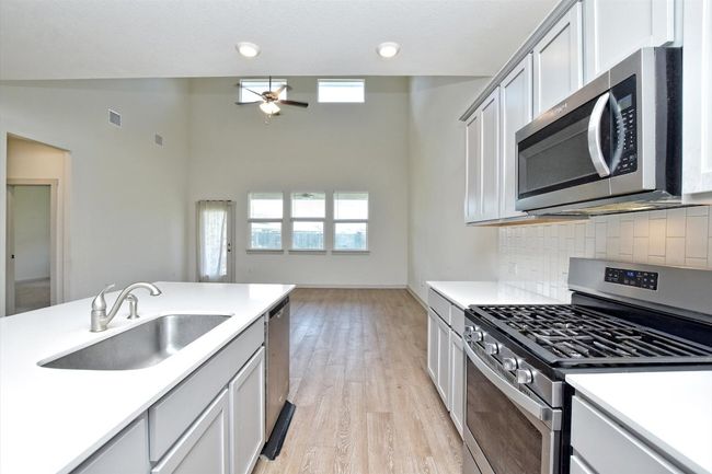 Kitchen with appliances with stainless steel finishes, a sink, plenty of natural light, decorative backsplash, and a high ceiling | Image 11