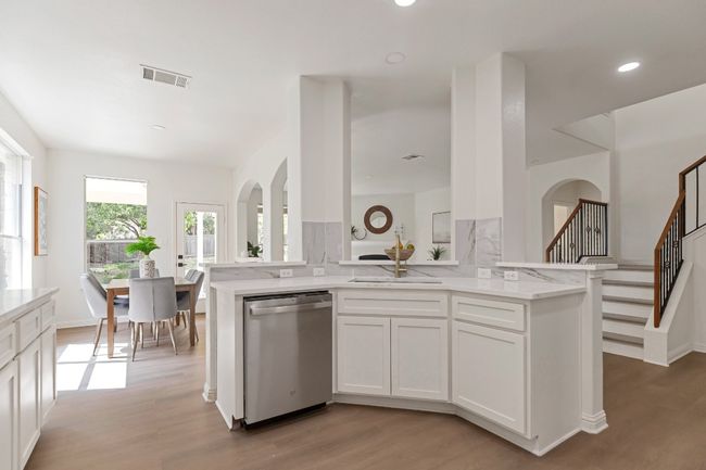 Kitchen with stainless steel dishwasher, light wood-type flooring, white cabinetry, light stone counters, and recessed lighting | Image 8