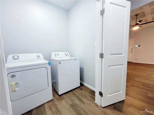 Laundry area featuring baseboards, a ceiling fan, independent washer and dryer, laundry area, and light wood finished floors | Image 20