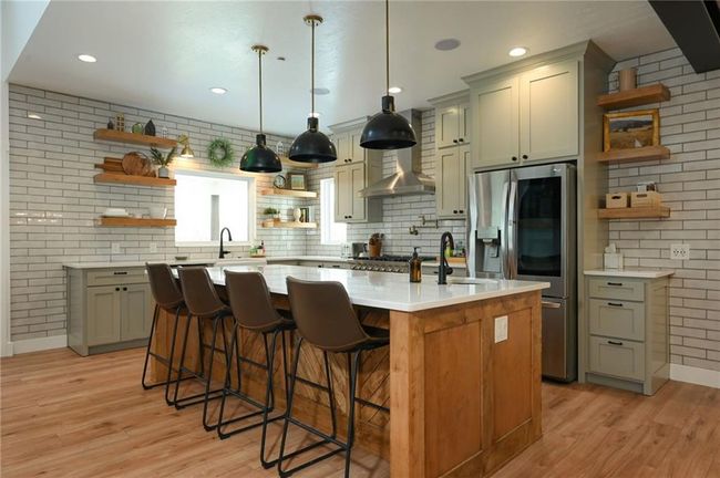 Kitchen with open shelves, stainless steel fridge, a sink under the window, light LVP flooring, and quartz countertops | Image 14