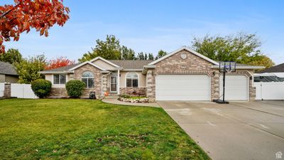 Ranch-style home featuring a front yard and a garage | Image 1