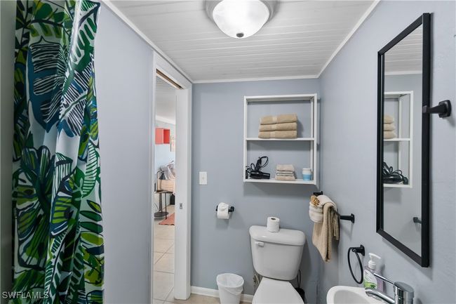 Bathroom with tile patterned flooring, toilet, crown molding, sink, and curtained shower | Image 20