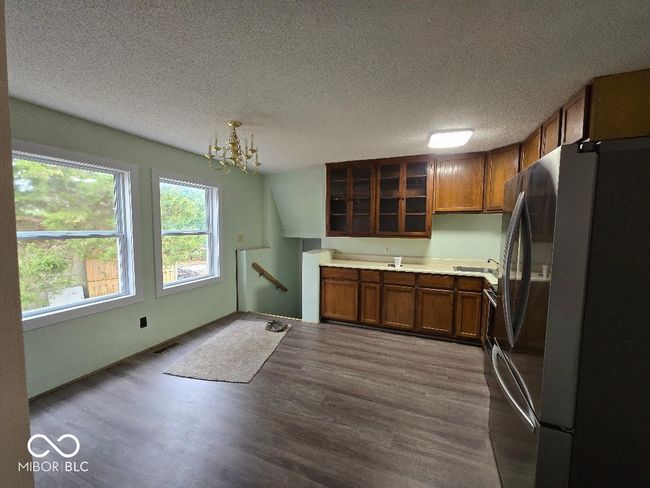 kitchen featuring glass insert cabinets, brown cabinets, dark wood finished floors, and freestanding refrigerator | Image 15