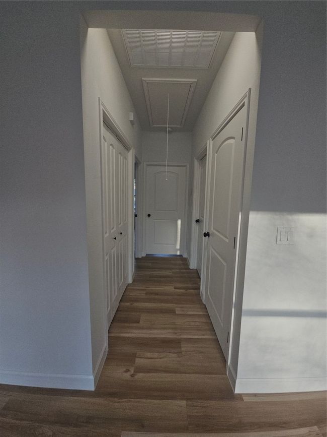 Hallway featuring attic access, wood finished floors, baseboards, and visible vents | Image 17