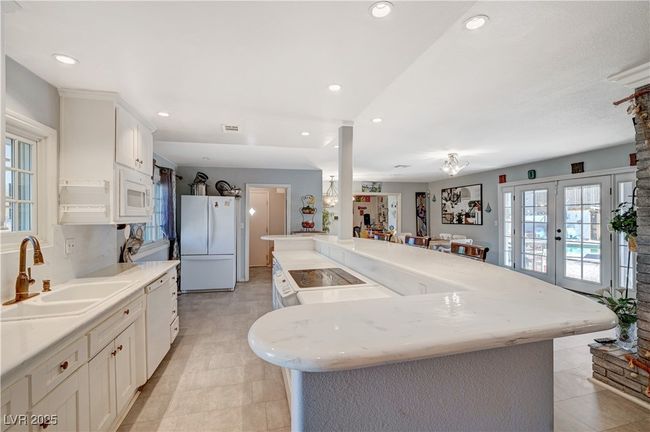 Kitchen with white appliances, a sink, white cabinets, light tile patterned floors, and recessed lighting | Image 45