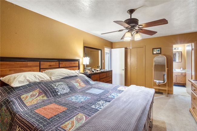 Bedroom featuring light carpet, ensuite bath, ceiling fan, and a closet | Image 18