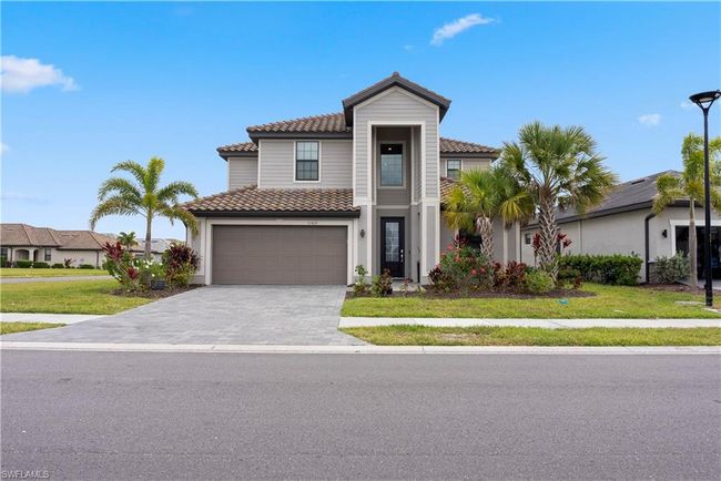 View of front of house featuring a tile roof, decorative driveway, a front yard, and a garage | Image 4