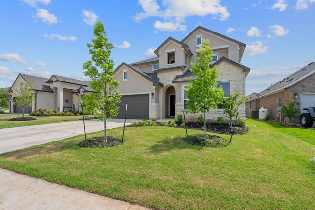 Traditional home featuring an attached garage, stone siding, a front yard, and concrete driveway | Image 27