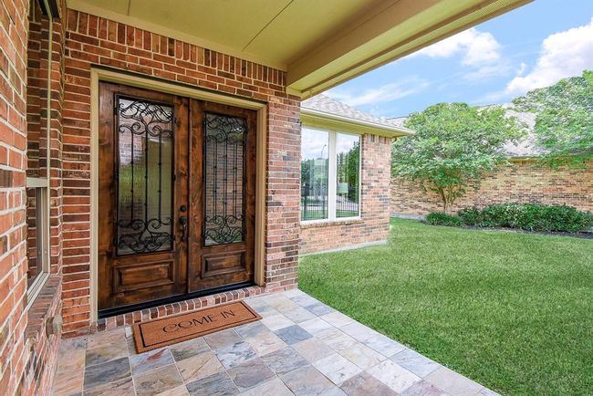 Ornate wrought iron details on solid wood double doors with glass insert is sure to impress guests! | Image 7