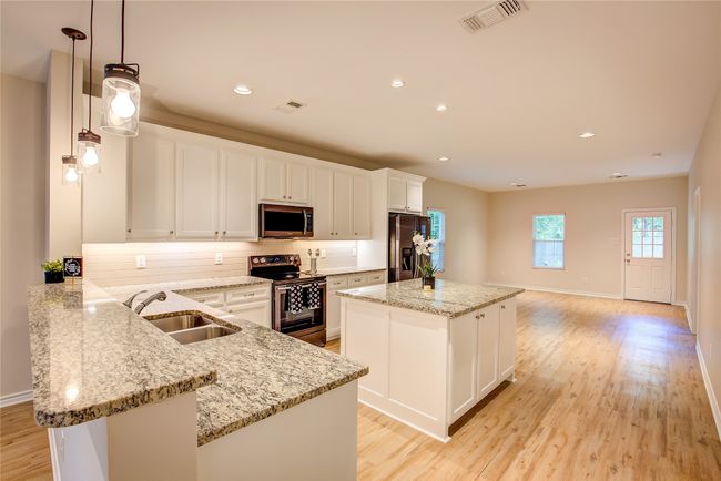 Kitchen featuring appliances with stainless steel finishes, a kitchen island, backsplash, light wood finished floors, and recessed lighting | Image 8