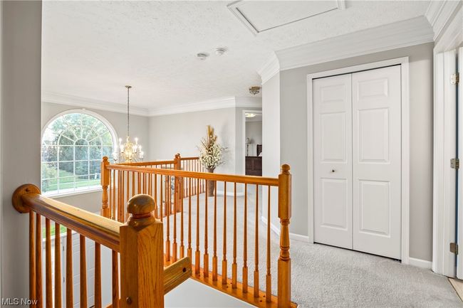 Hall featuring a textured ceiling, a chandelier, crown molding, and light colored carpet | Image 19