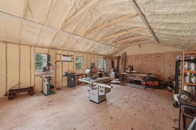 Misc room featuring a workshop area, lofted ceiling, and a wall mounted AC | Image 35